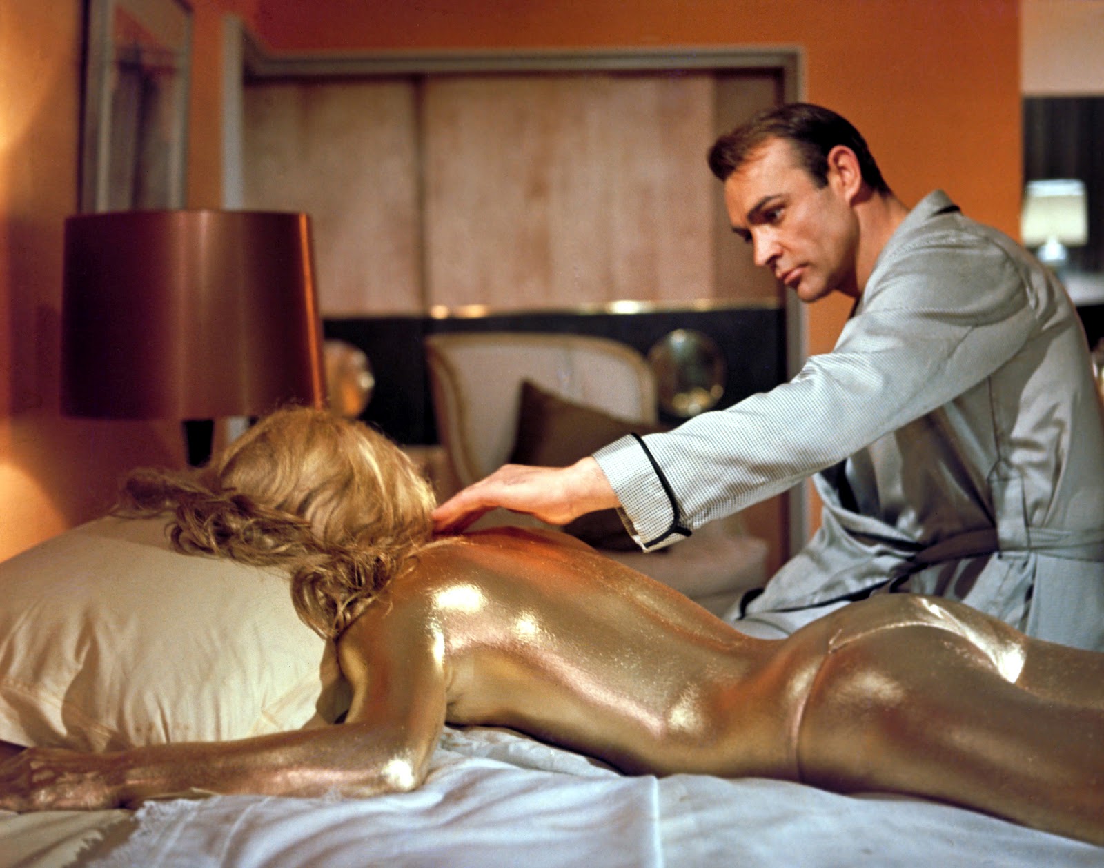 James Bond (Sean Connery) examines the body Jill Masterson (Shirley Eaton) after receiving the Goldfinger treatment.