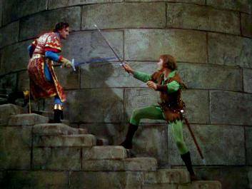 Sir Guy of Gisbourne (Basil Rathbone) backs up the castle stairs as he fends off Robin Hood (Errol Flynn).
