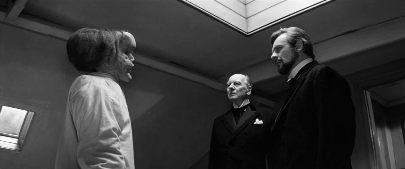 John Merrick (John Hurt) surprises hospital governor Francis Carr-Gomm (John Gielgud) and Dr. Treves (Anthony Hopkins).