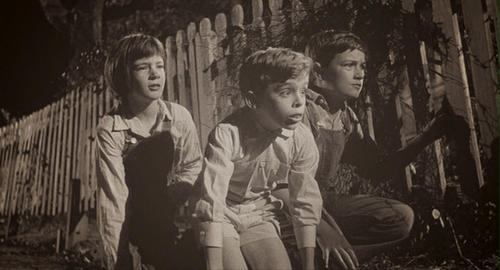 Scout Finch (Mary Badham), Dill Harris (John Megna), and Jem Finch (Phillip Alford) spy something very interesting.